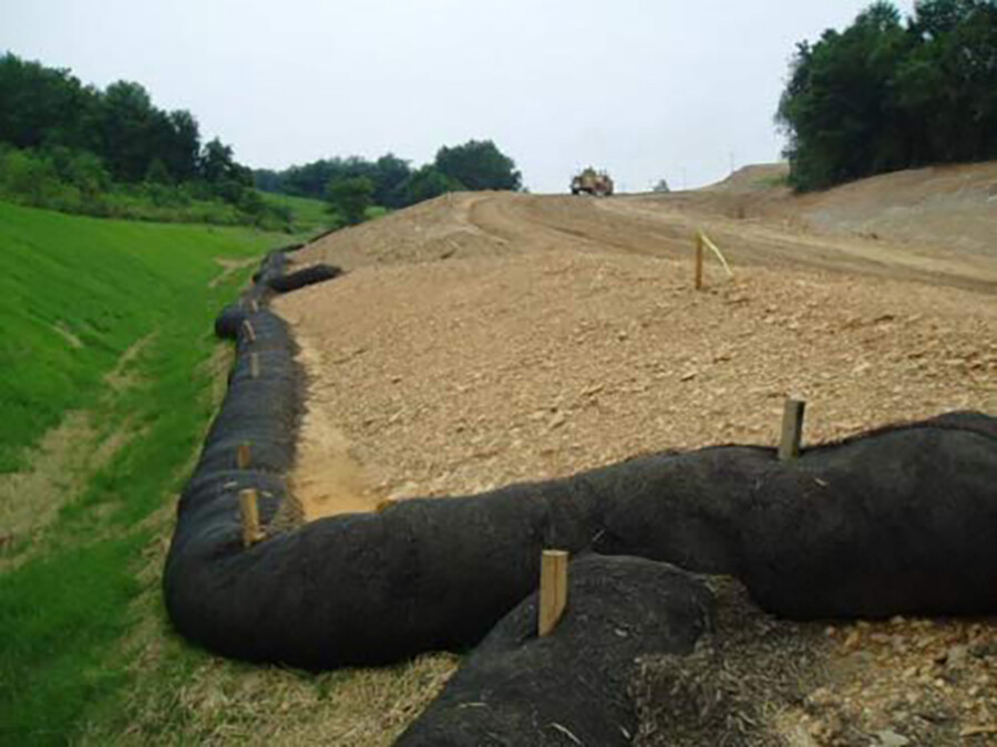 Silt sock erosion control installed along a graded roadway embankment