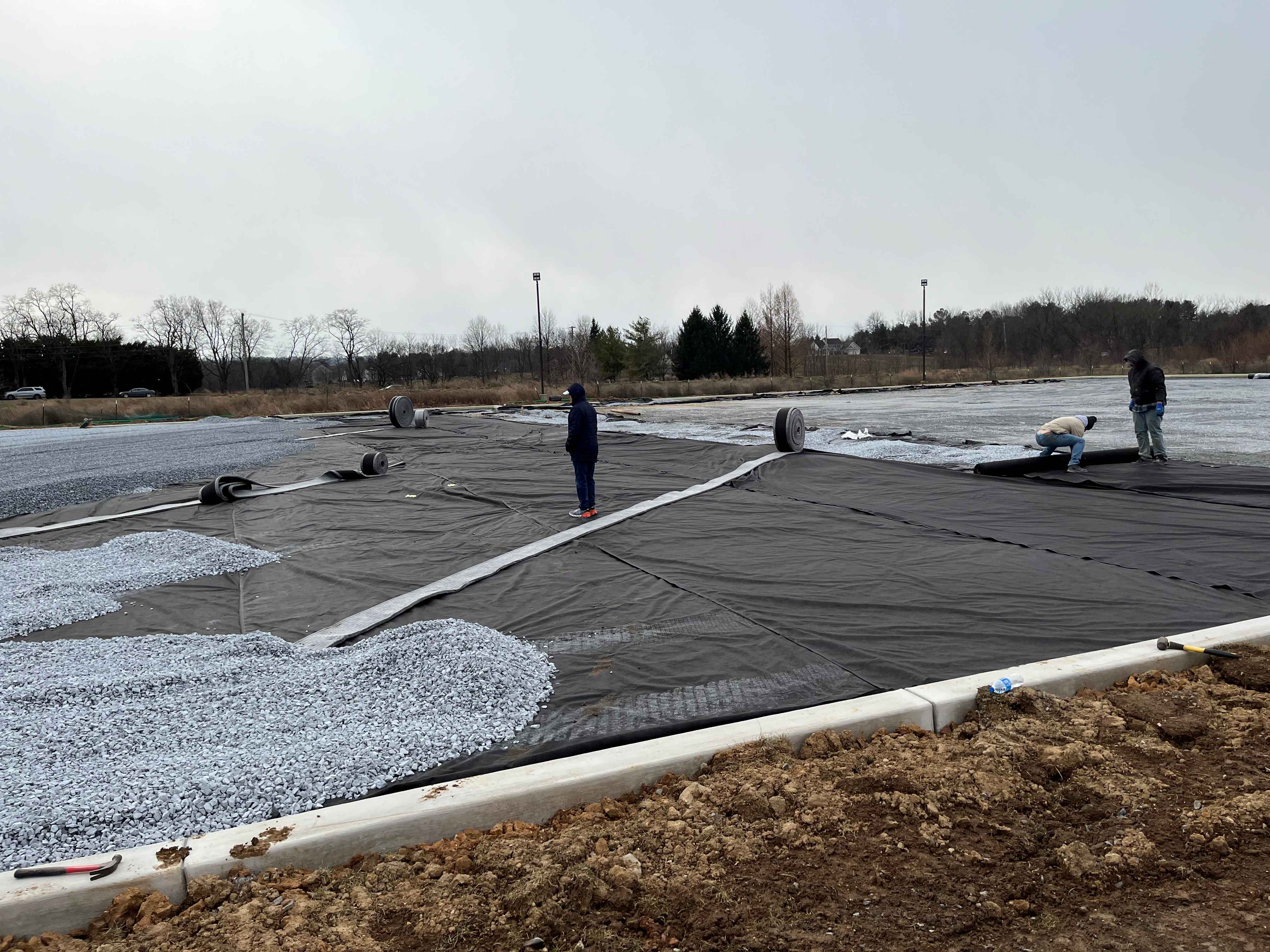 Crew installing geotextile fabric and stone during a grading and drainage installation